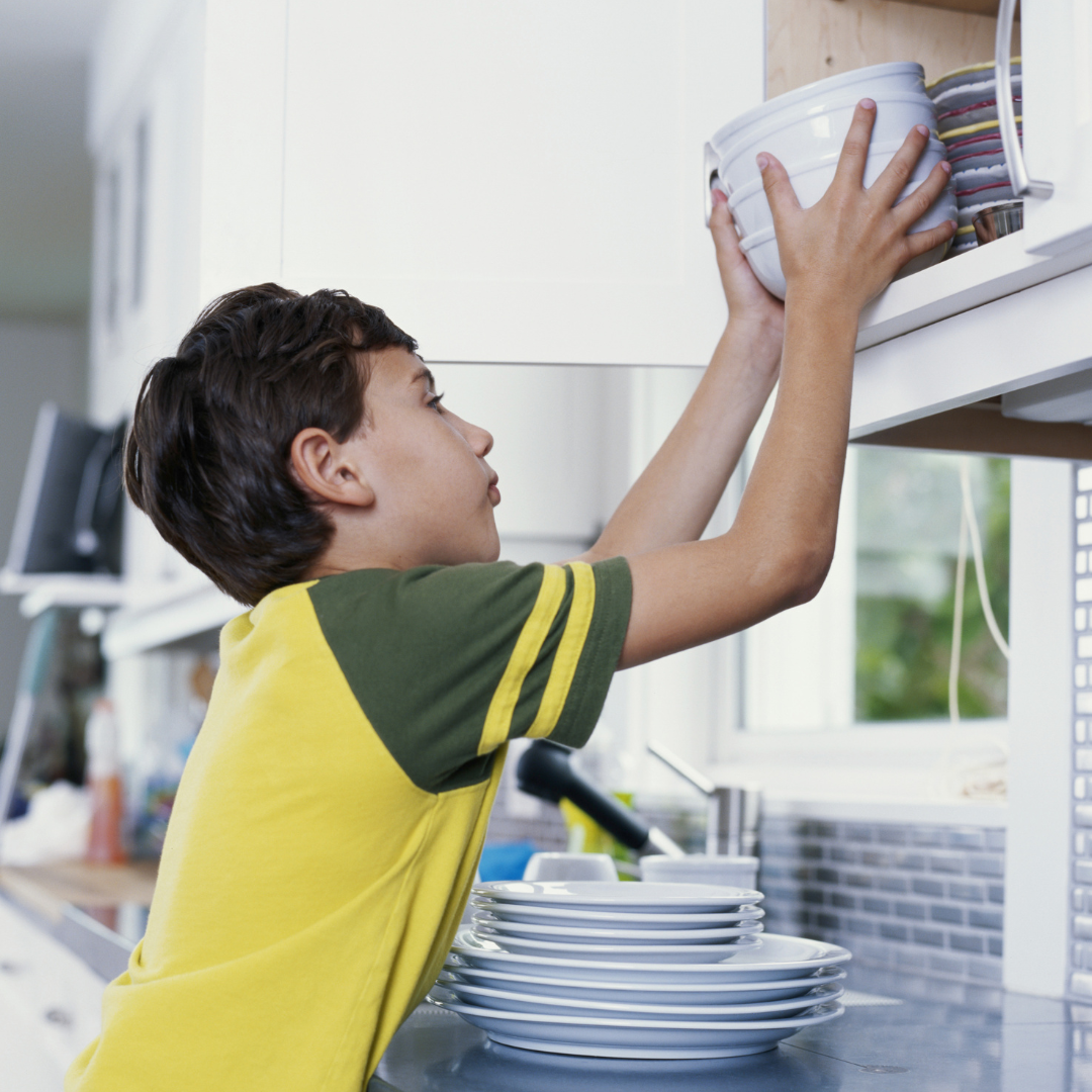 Kids returning items to labelled kitchen shelves as part of the weekly cabinet reset
